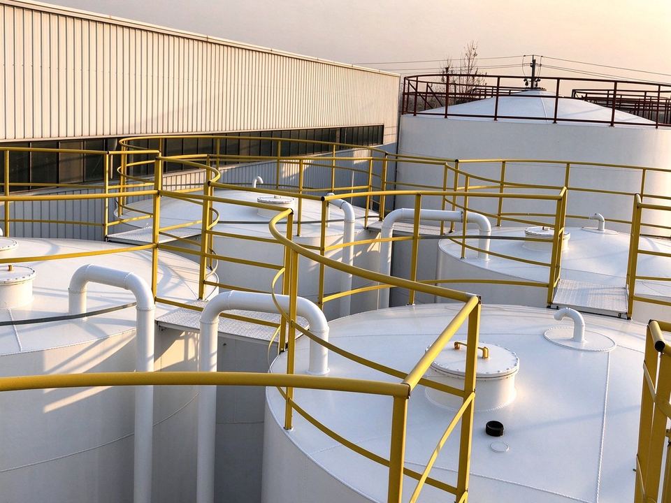 Outdoor base-oil tank farm with fill pipework and bund wall