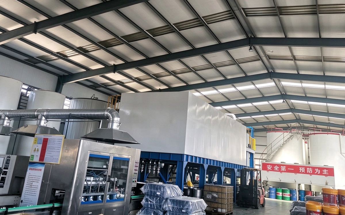 Production hall at Zoucheng: blending kettles on the left, filling machine and palletised goods in the centre, base-oil tanks at the far end