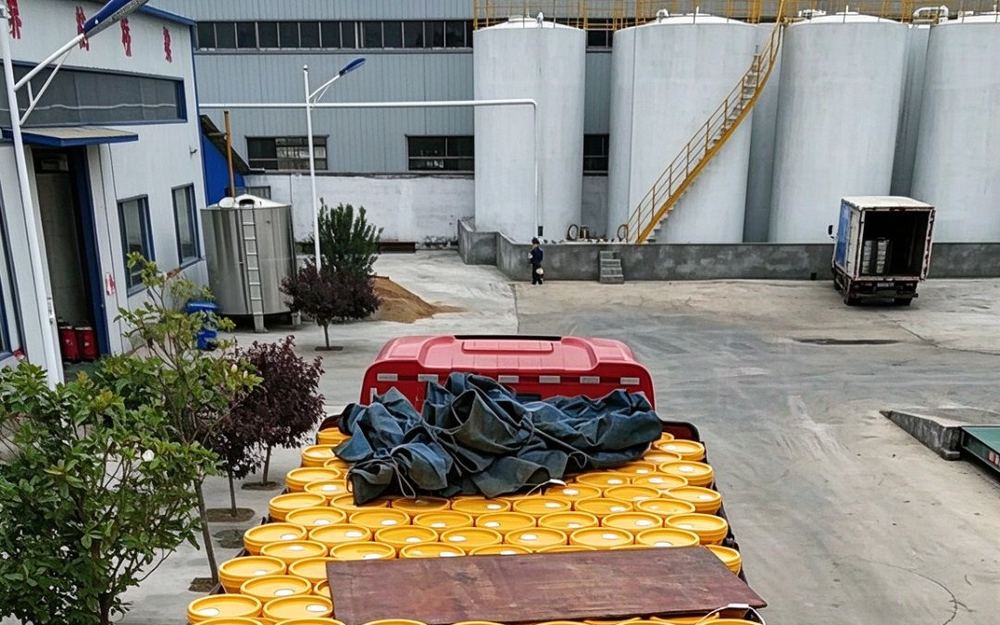 Filled pails loaded on a dispatch truck in front of the base-oil tanks